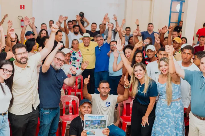 Irineia Barbosa entre apoiadores com as mãos erguidas em encontro político em Cruzeiro do Sul